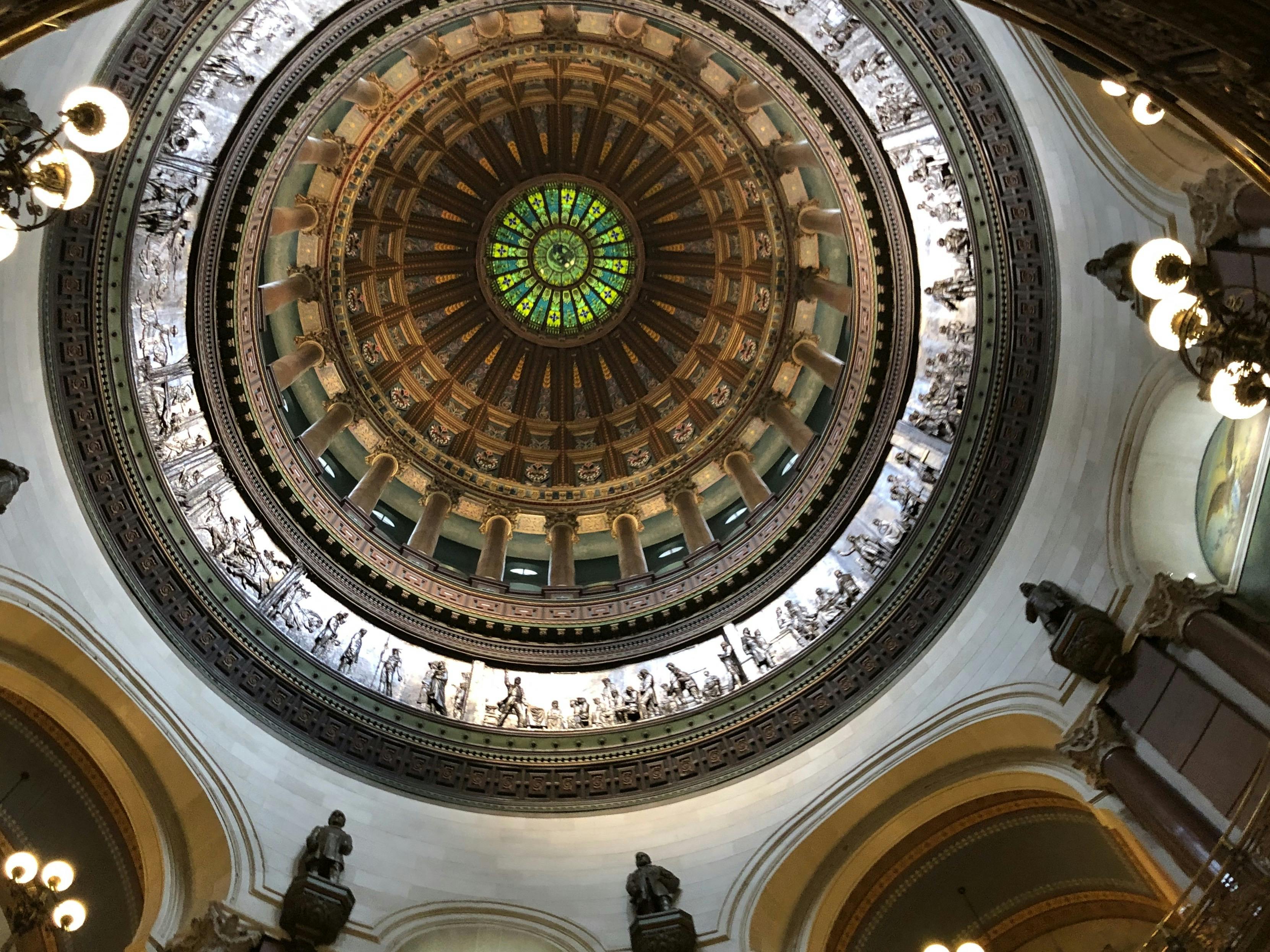 A circular, dome-shaped ceiling with statues lining the circumference. A stained glass window is at the very top.
